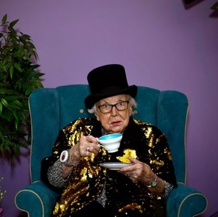 Our nan, Betty, in a top hat and a gold sequin jacket, drinking tea in an armchair
